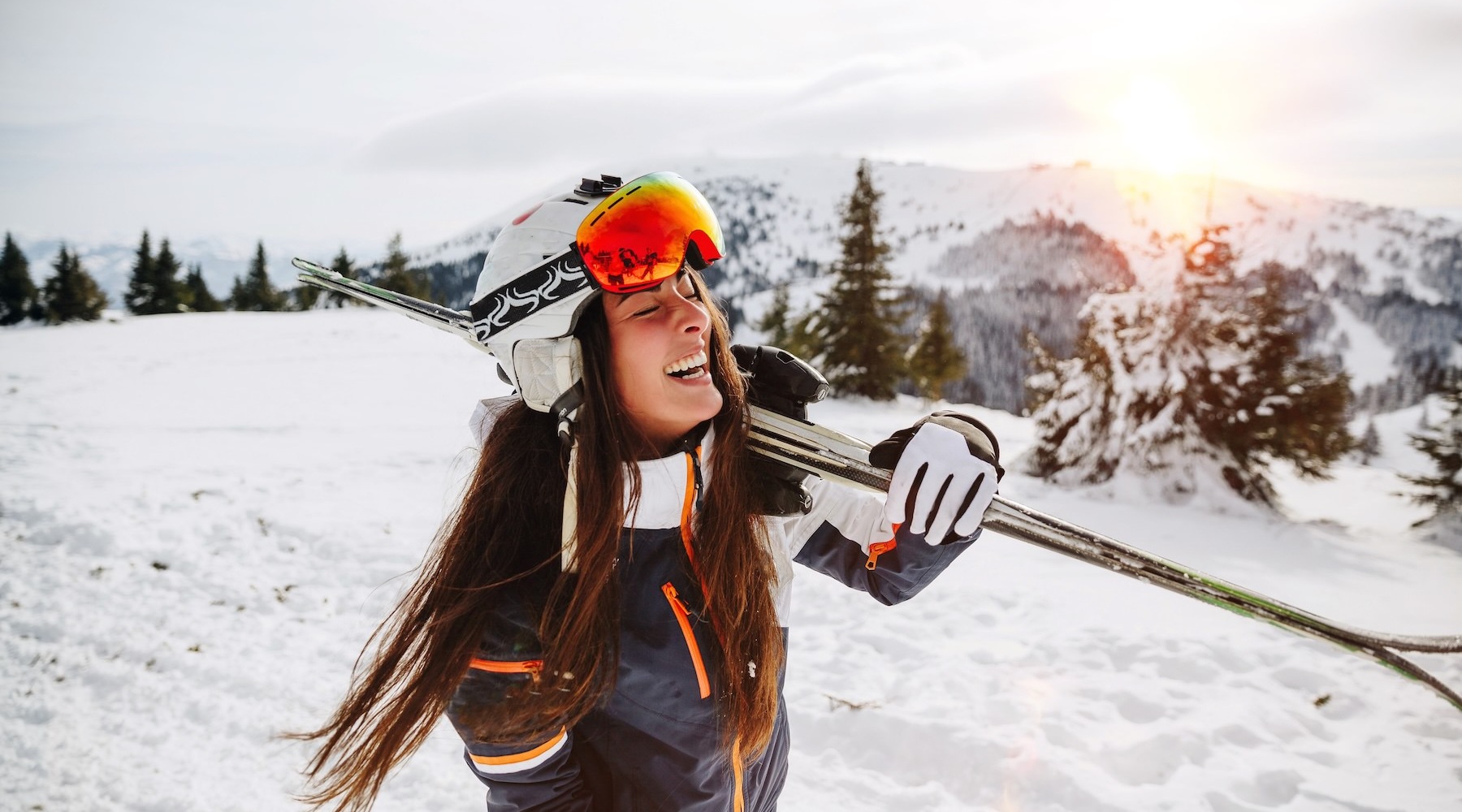 a woman walking in the snow carrying skis